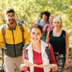 Smiling Beautiful Brunette Holding Map And Leading The Rest Of H